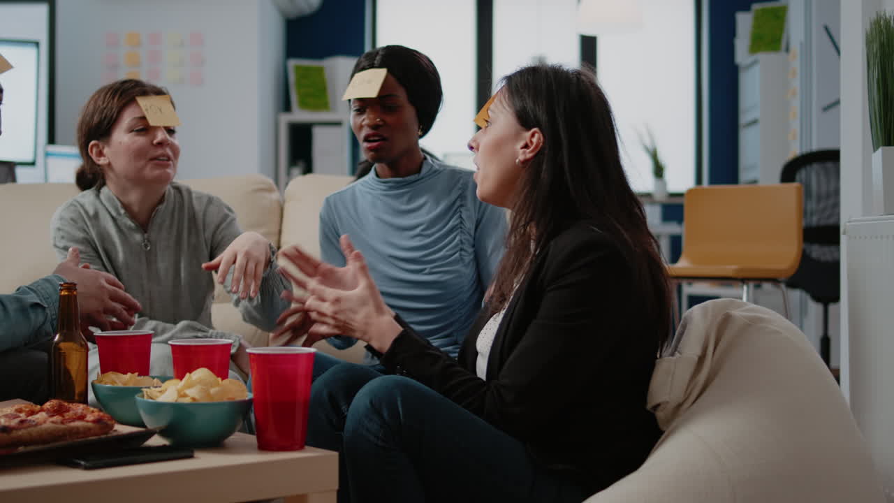 Coworkers playing charades game with sticky notes after work