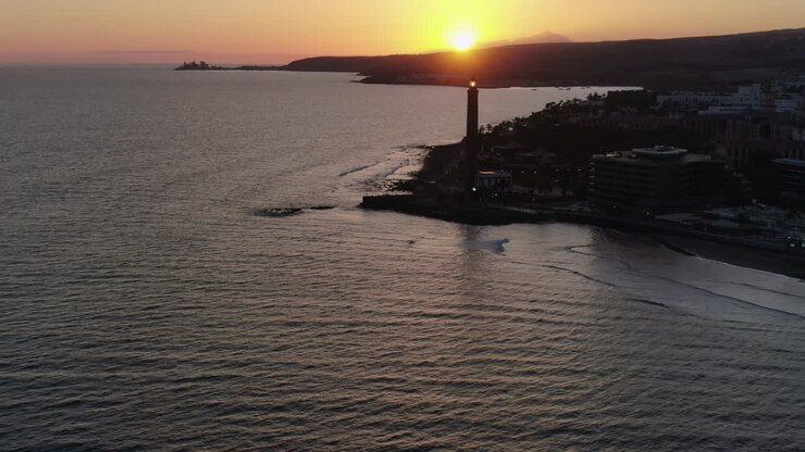 Vista aérea do farol e da praia de Maspalomas com o sol se pondo sobre o oceano. Gran Canaria, Ilhas Canárias, Espanha.