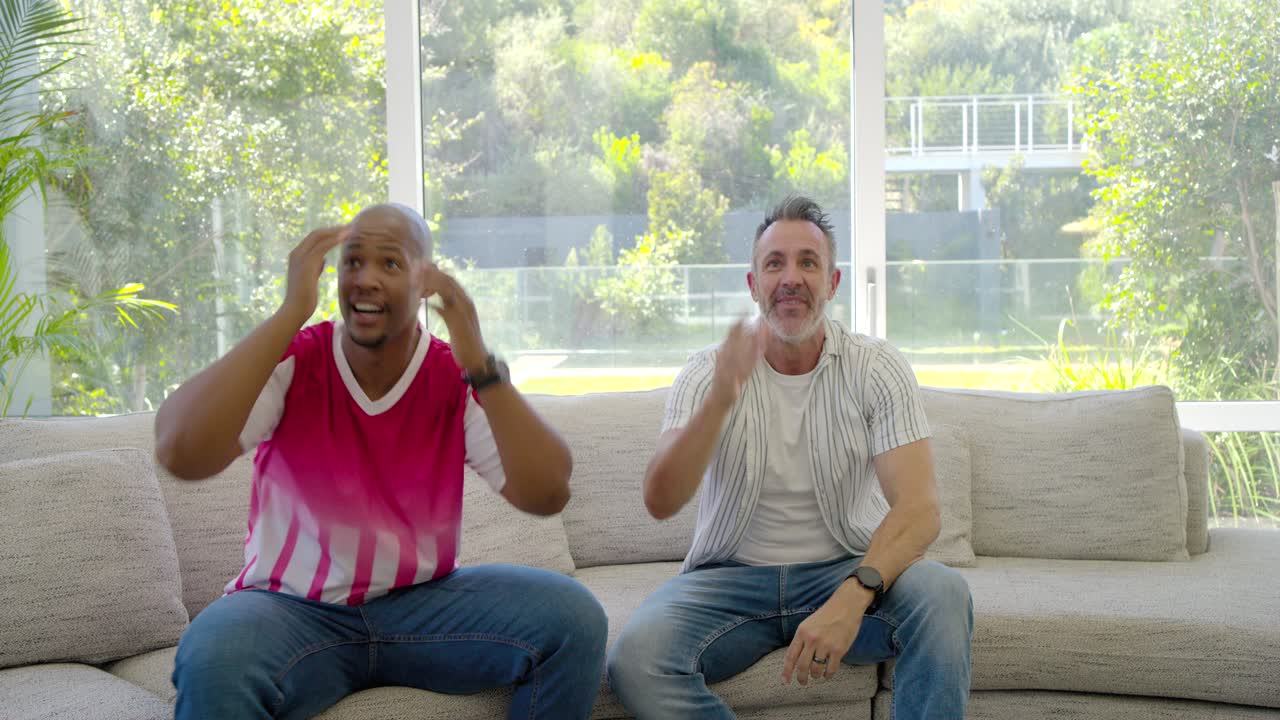 Vertical video: Two friends watching big play on TV, men standing, cheering as woman bringing tray