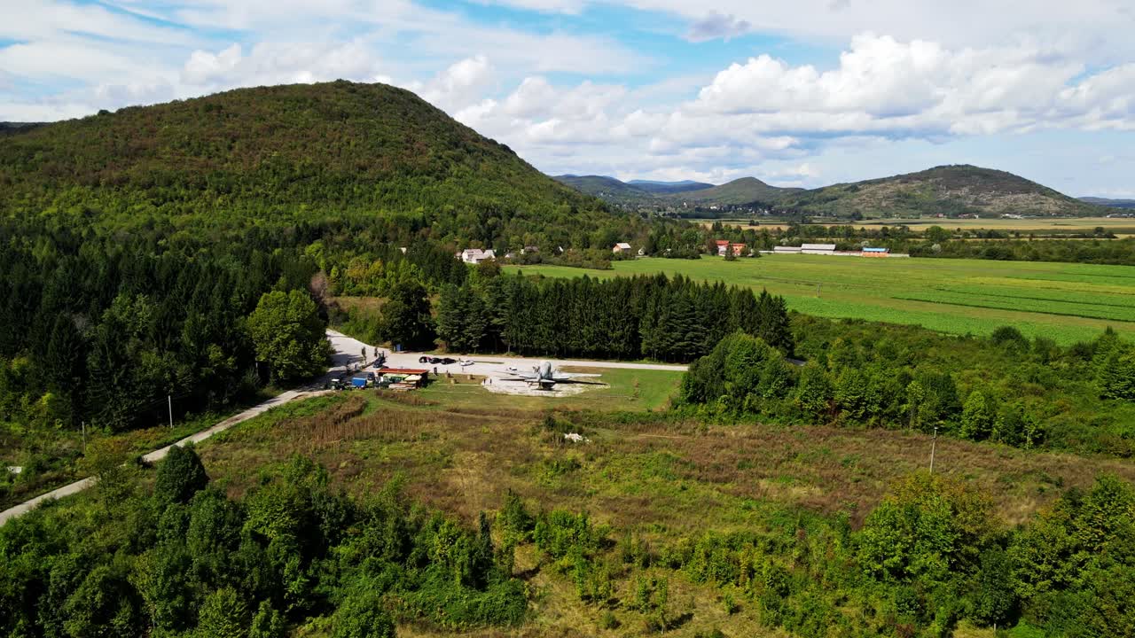 Verlaten vliegtuigwrak in het Bosnische landschap, omgeven door bos, velden en glooiende heuvels in een afgelegen, landelijke omgeving