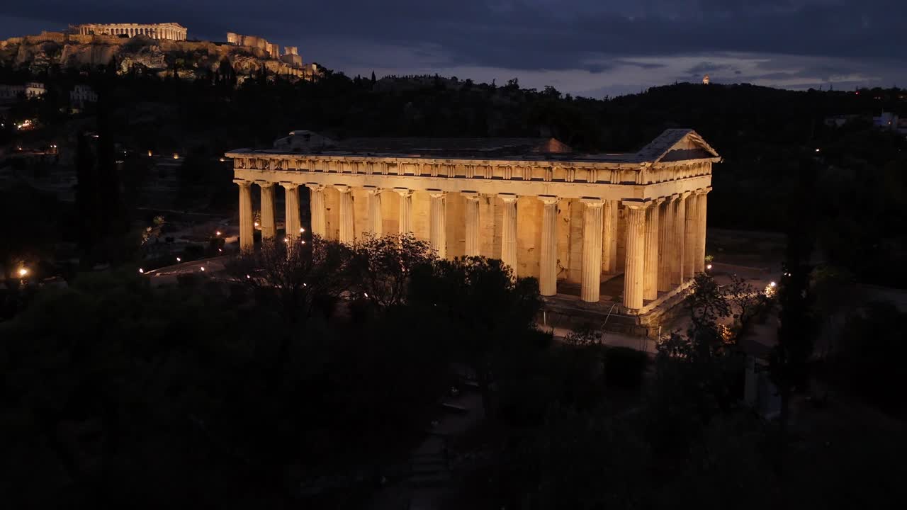 Athens,Aerial view forward towards iconic Hephaestus Temple,one of the most well preserved in Greece and Acropolis hill at the background,both beautifully illuminated
