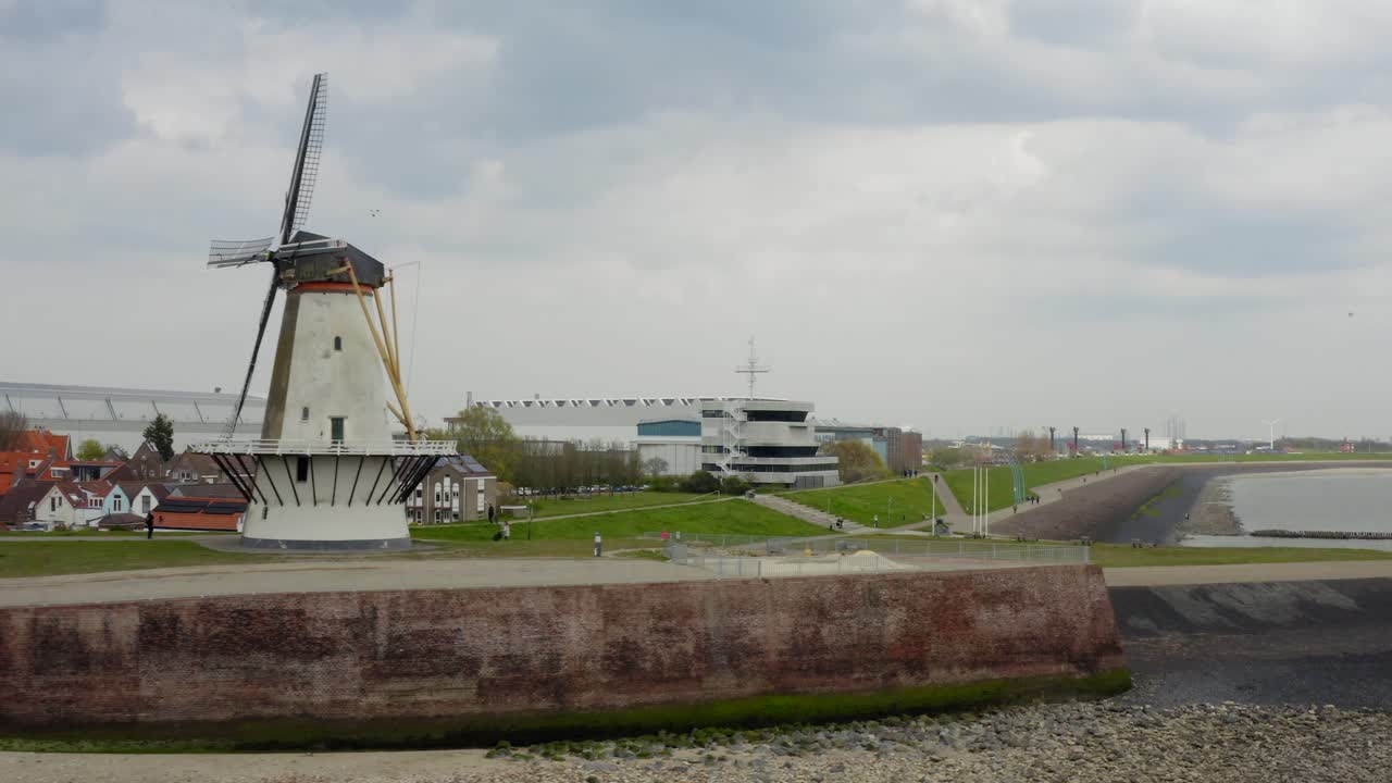 네덜란드 블리싱겐에 있는 빨간 재킷을 입은 바이커와 일부 사람들과 함께 요새화된 부두 위의 공중 로우 패스