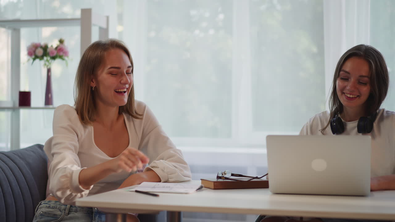 Lachende Studenten geben sich High Five und arbeiten weiter an ihrer Aufgabe