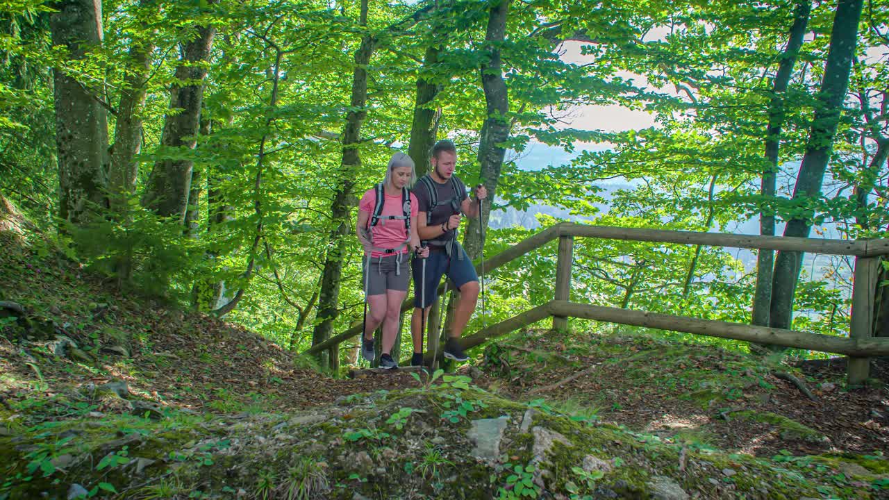 Active couple of hikers coming from forest and reaching panoramic viewing point
