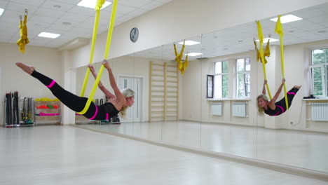 the concept of sports for a healthy lifestyle. the girl has been aerology of antigravity relaxes and swings on the canvas in a white room