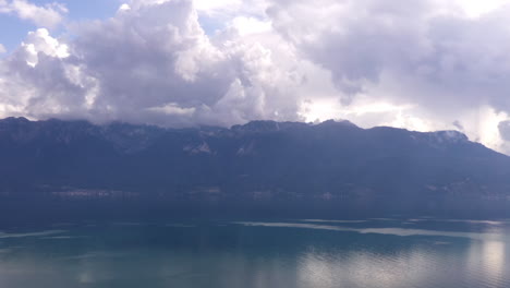 aerial hyper lapse of clouds rolling over mountains near lake