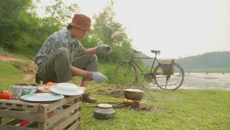 scenic view of a male guy breaking sticks and putting in a stove for cooking along the riverside in rural countryside in loc bin, district of lạng sơn province in the northeast region of vietnam