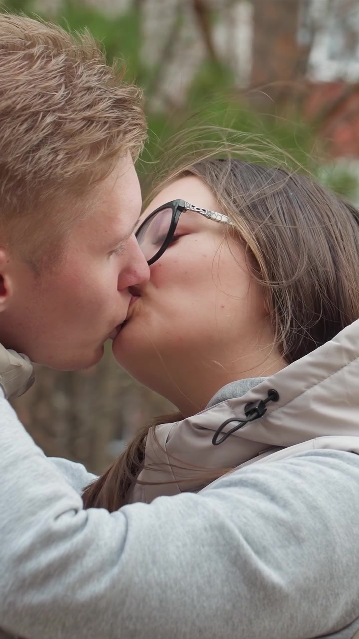 Uomo e donna si fronteggiano da vicino all'aperto. La coppia continua a stringersi l'uno all'altra contro una vegetazione sfocata. L'angolazione della telecamera è fissa con un movimento stabile, concentrandosi da vicino sulla coppia.