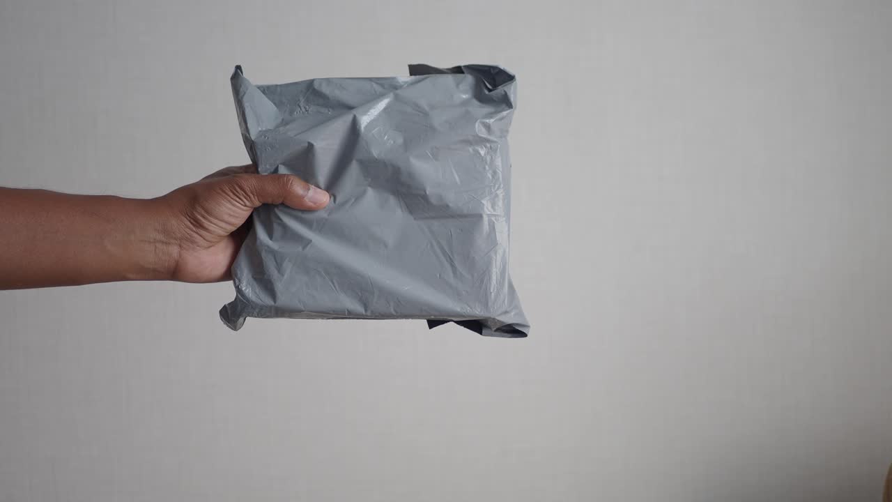 회색 플라스틱 패키지를 들고 있는 손