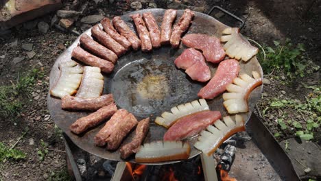 Traditional-Romanian-foods-mititei,-slanina-and-pork-meat-cooking-over-wood-fire