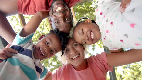 diverse family forms a circle at home, smiling faces looking down at the camera