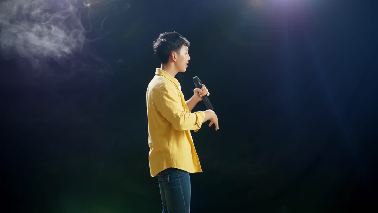 vista lateral de un joven asiático con un micrófono y rap en el fondo blanco de humo negro