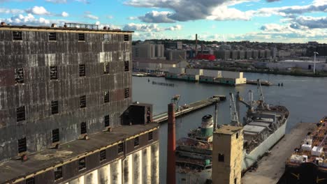 Aerial-pull-back-next-to-massive-grain-terminal-and-old-ship-in-an-industrial-harbor-in-Brooklyn-New-York-City