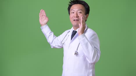 성숙한 일본인 남성, 초록색 배경의 의사
