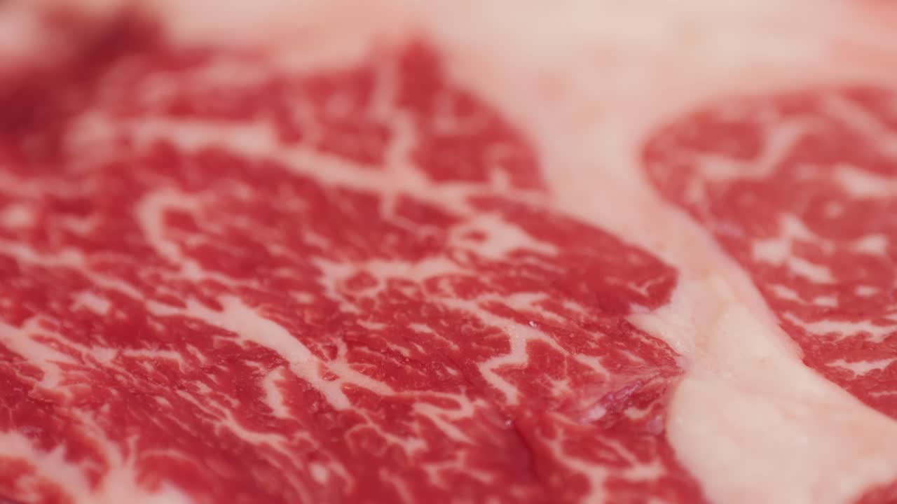 Fresh marbled beef with pepper, salt and rosemary close-up macro. Preparation to cook juicy steak on grill. Premium organic raw wagyu meat. High quality 4k footage