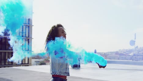 fashionable young woman on urban rooftop using a smoke grenade