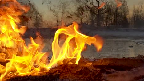 Close-up-shot-of-burning-oil,-while-remaining-oil-stands-in-the-back-ground-surrounded-by-melted-snow