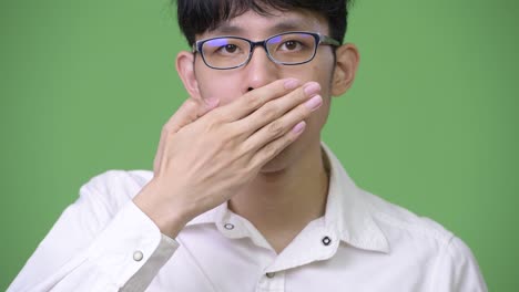 young asian businessman covering mouth as speak no evil concept