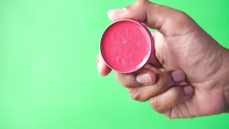 cerca de la mano del hombre sosteniendo gelatina de petróleo contra un fondo verde