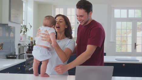 Loving-Transgender-Family-With-Baby-At-Home-Together-With-Laptop-On-Kitchen-Counter