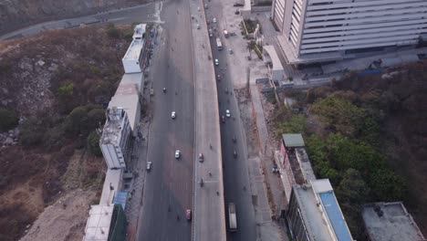 a slow tilt up reveals the aerial view of biodiversity flyover meeting with the dallas center road and gadchibowli - old mumbai highway with biodiversity park in left side and wells fargo on right