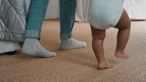 baby taking first steps toddler learning to walk with mother gently helping infant teaching child at home motherhood trust