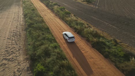 aerial tracking shot of car driving on dirt road at golden hour, south africa