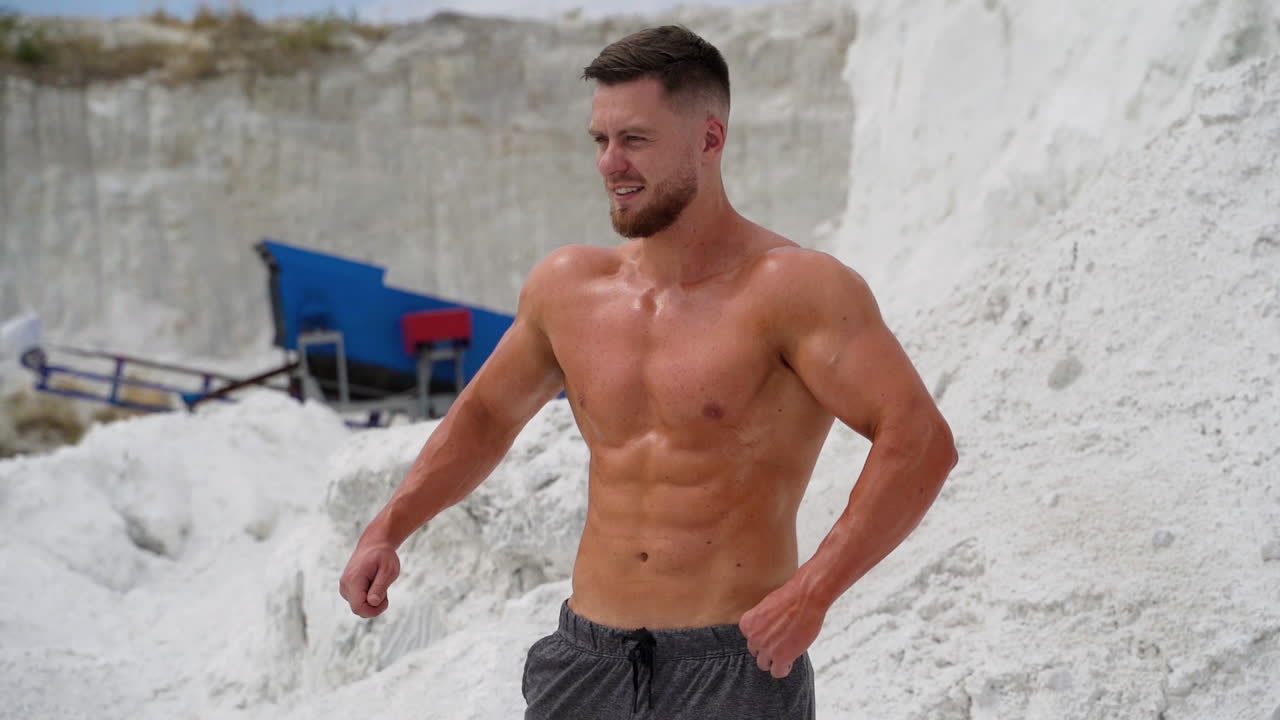 Man showing her perfect abs. Well built bodybuilder posing in the mountains