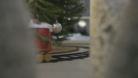 close-up of a driving illuminated festive toy train with decorated christmas tree, warm lighting