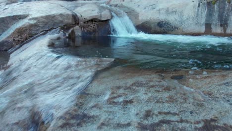 Toma-Panorámica-Izquierda-De-Una-Pequeña-Cascada-Que-Se-Derrama-En-Una-Piscina-Profunda-Que-Se-Está-Desbordando