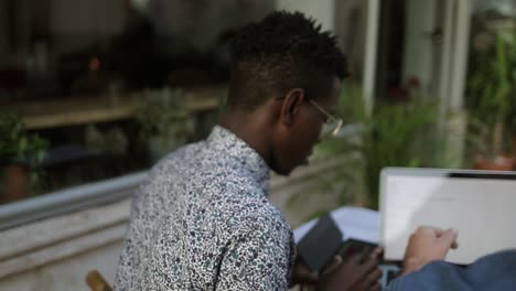 Multiethnic-men-using-laptop-and-smartphone-in-outdoor-cafe