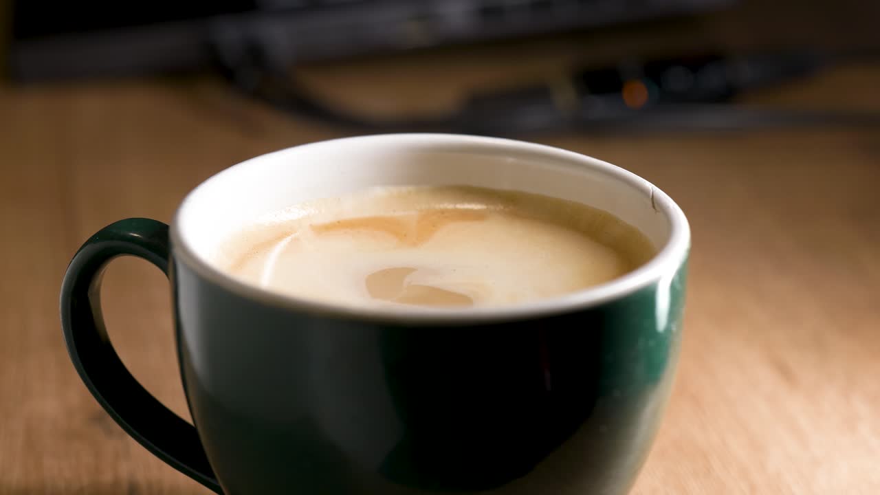 Primo piano di una mano che inzuppa un biscotto in una tazza di caffè, creando un'atmosfera accogliente e calda. Concetto di colazione