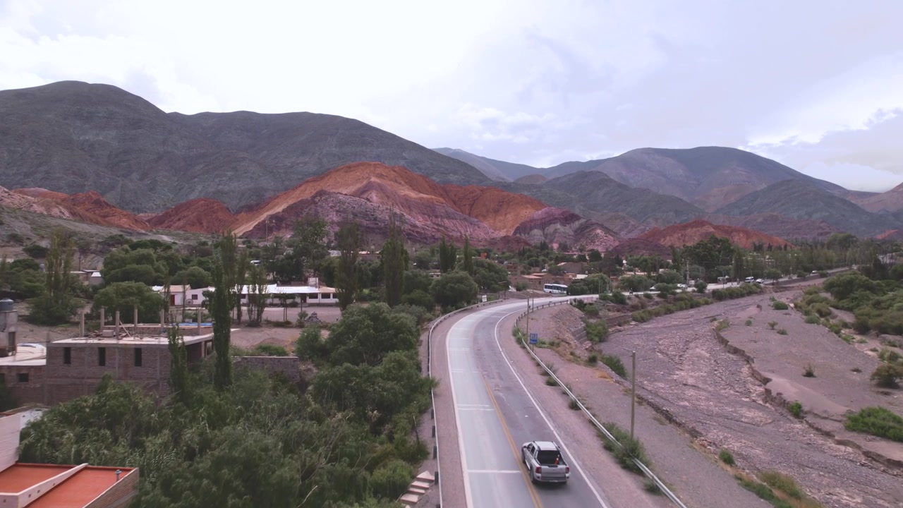 Vista aérea 4K con dron de Purmamarca, Jujuy, Argentina. Colorido pueblo andino rodeado por el icónico Cerro de los Siete Colores, con formaciones montañosas únicas de color rojo, naranja y verde
