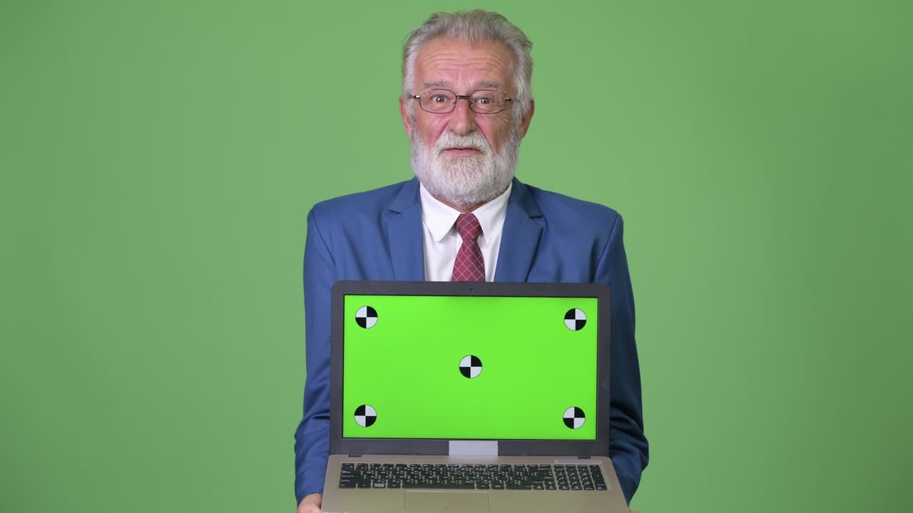 Empresário sênior barbudo e bonito contra fundo verde.