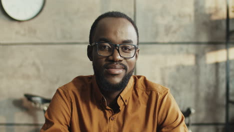 portrait of cheerful office worker with glasses smiling to camera while sitting at table at workplace