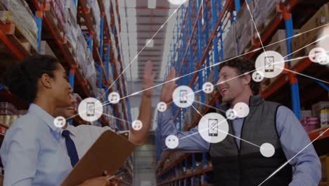 Animation-of-network-of-icons-over-diverse-team-of-supervisors-high-fiving-each-other-at-warehouse