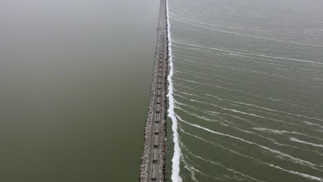 el tren de mercancías transporta piedra por el mar nublado, con una antena de inclinación ancha y alta.