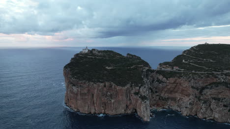 Cape-Caccia,-Sardinia:-remote-aerial-view-of-the-cliff-and-lighthouse-located-on-the-cape-on-the-island-and-during-sunset