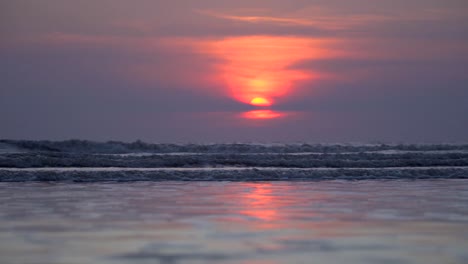 handheld shot of romantic sunset at beach, purple sky, golden sun, relaxing purple tidal waves , incredible seashore in india