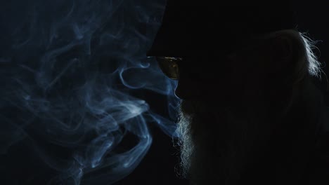 cool, bearded man holds burnt match in smoky, dark jazz portrait