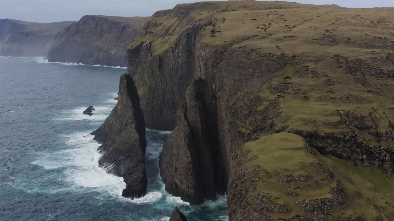 tomada de avión no tripulado de geitaskorardrangur mar pila en vagar durante el cielo nublado, isla de feroe