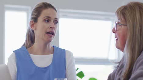 Female-health-worker-talking-to-senior-woman-at-home