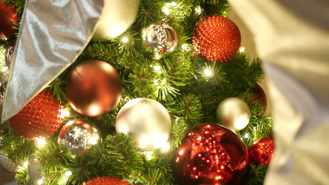 primer plano de un árbol de navidad al aire libre decorado festivamente con bolas rojas brillantes en un fondo de hadas brillantes borrosas. luces de guirnaldas desenfocadas, efecto bokeh. feliz navidad y feliz concepto de vacaciones.