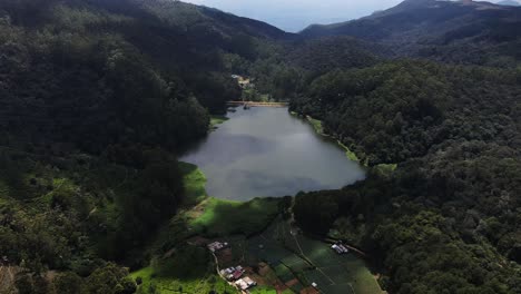 las sombras se mueven lentamente sobre el depósito azul claro entre las altas colinas verdes llenas de árboles altos en la vasta naturaleza de sri lanka en un día nublado en nuwara eliya