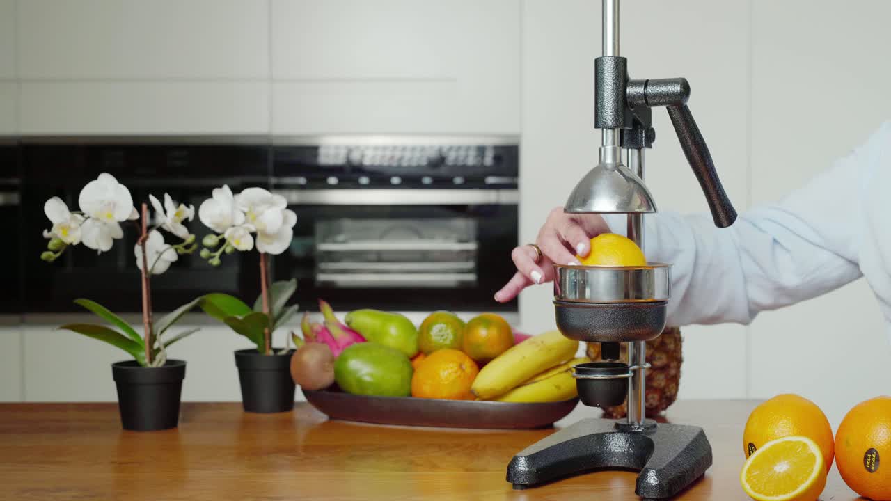 Caucasian female using hand press fruit juicer making fresh orange juice, close up
