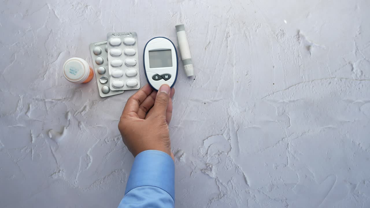 분홍색 배경에 있는 당뇨병 측정 도구와 알약의 클로즈업