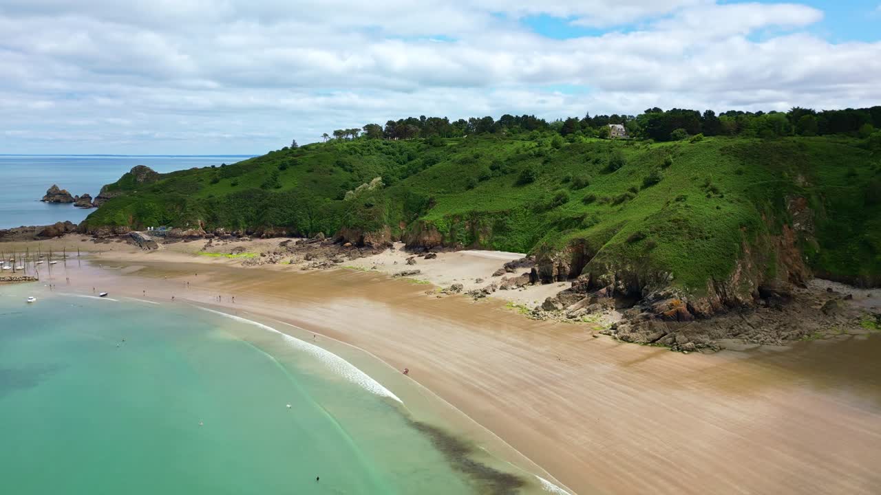 Gwin Zégal sunlit tropical beach near its spectacular cliffs with green hills in background, Côtes-d'Armor, Brittany, France.