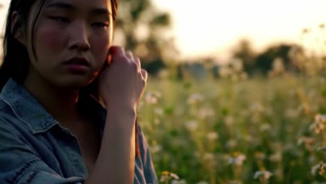 a young woman stands contemplatively in a blooming field under the warm glow of sunset, capturing the essence of introspection and natural beauty