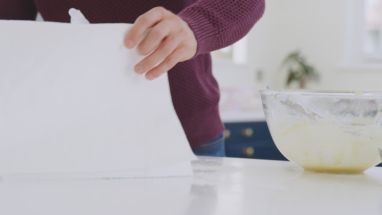 hombre limpiando el mostrador de la cocina con spray y tela después de hornear el pastel