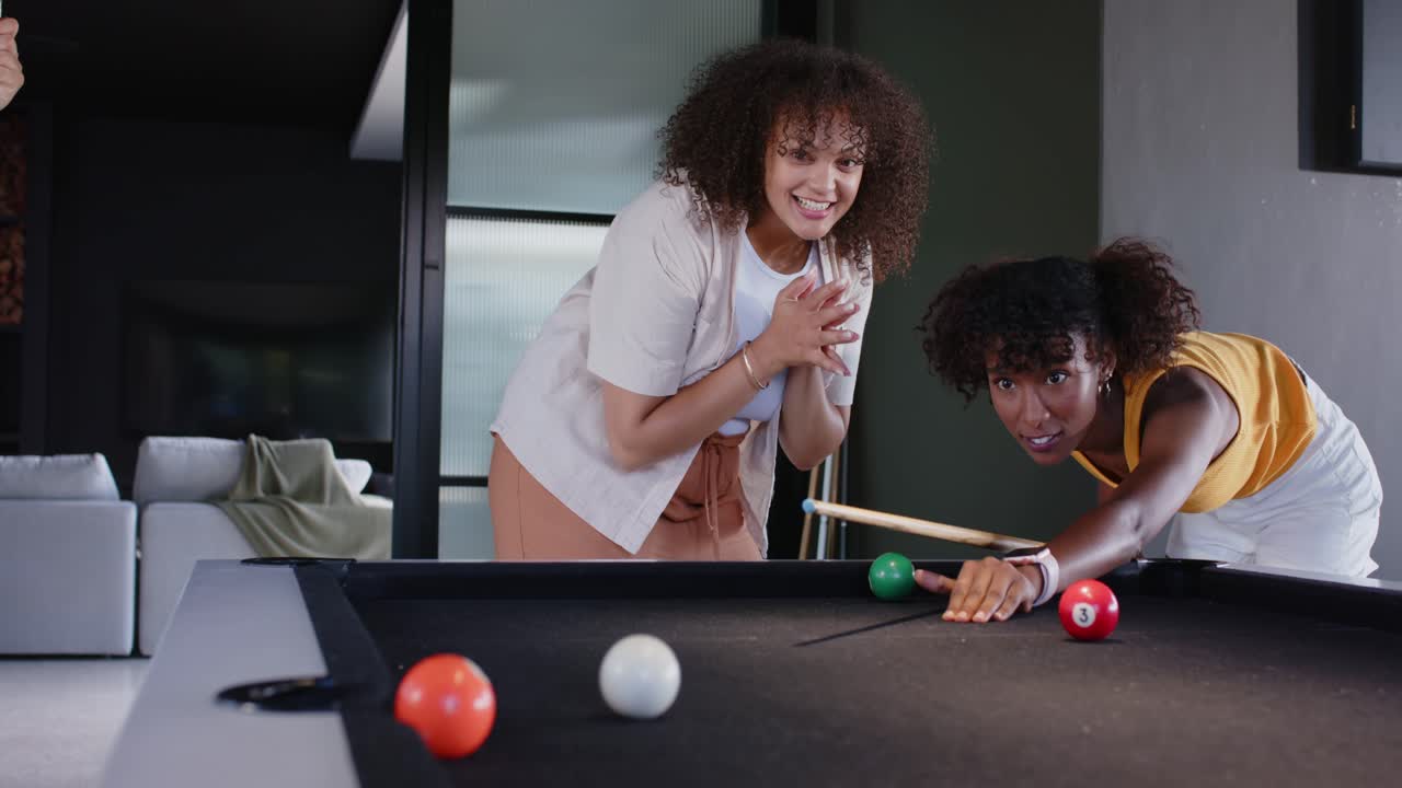 African American women friends playing on black felt table at home spotting pocket celebrating